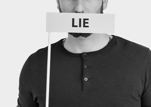 Person holding 'LIE' sign